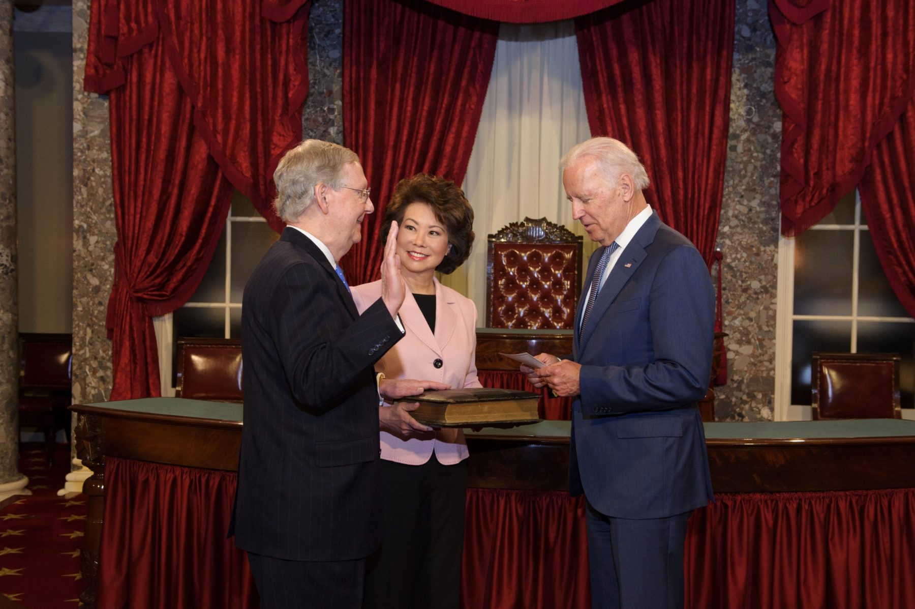Elaine Chao holds the Bible for husband, U.S. Senate Majority Leader Mitch McConnell as he's sworn in by Vice President Biden at the U.S. Capitol.